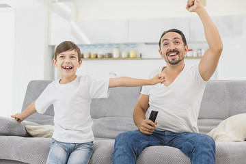 Young father and his son watching world soccer championship on the sofa