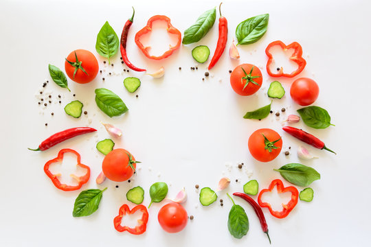 Colorful salad ingredients pattern made of tomatoes, pepper, chili, garlic, cucumber slices and  basil on white background. Cooking concept. Top view. Flat lay. Copy space