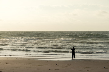 Naklejka premium 朝焼けの海岸を歩く女性 / リラックスイメージ