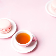Still life with french delicious dessert macaroons and cup of coffee on pink background with copy space