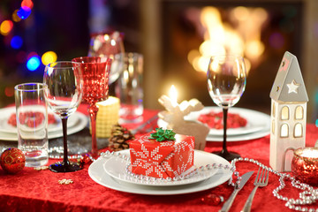 Beautiful table setting for Christmas party or New Year celebration at home. Cozy room with a...