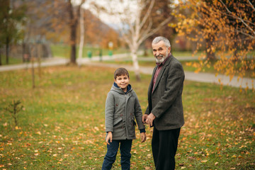 Obraz premium Grandpa and his grandson are walking in the park. The spend time together