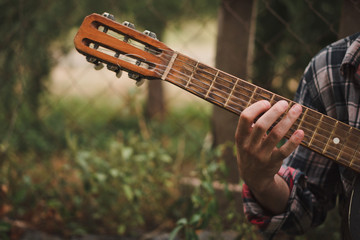 A man plays the old guitar in casual clothes. Close up.