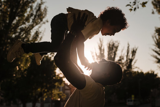 African father raises his son with his arms sunset background