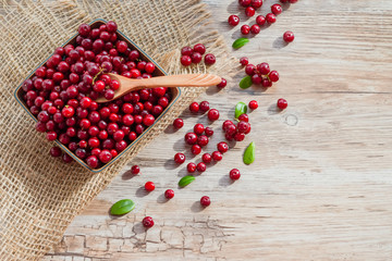 Red ripe fresh cranberry berry wooden plate on old wooden table, rustic style, cowberry copyspace
