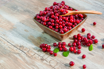 Red ripe fresh cranberry berry wooden plate on old wooden table, rustic style, cowberry copyspace
