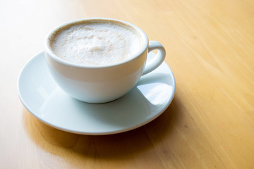 hot coffee cappuccino cup with milk foam on wood table background. Drinken latte art coffee on wooden table.Cup of cappuccino on the table, coffee shop background.
