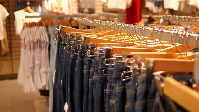 Hangers with a fashionable jeans clothes in store boutique - shopping discounts