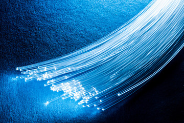 Bundle of optical fibers with lights in the ends. Blue background.