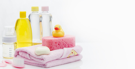 Fototapeta na wymiar Still life with baby hygiene and bath items, shampoo bottle, essential oil, baby soap, towel, pacifier, rubber toy, shower puff. Copy space for your text