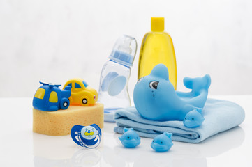 Still life with babt hygiene and bath items, shampoo bottle, essential oil, baby soap, towel, pacifier, rubber toy, shower puff