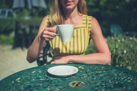 Woman drinking coffee in garden of cafe