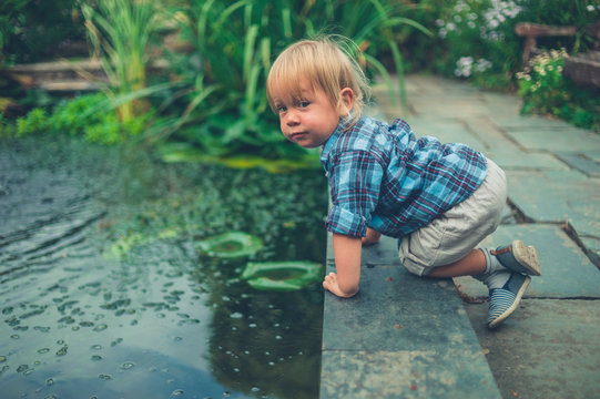 Little toddler playing near a pond