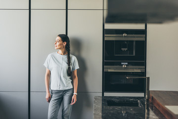 attractive young woman looking away in kitchen at home