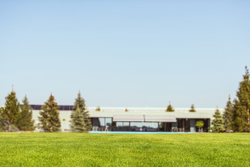 selective focus of green lawn and modern cottage under blue clear sky