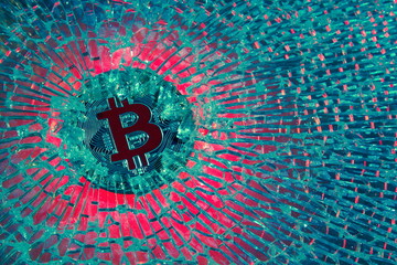 Bitcoin crypto currency bear market or depression concept, metal clamp squeezing  Bitcoin physical coin , crisis on cryptocurrency investment trading metaphor.On broken glass background
