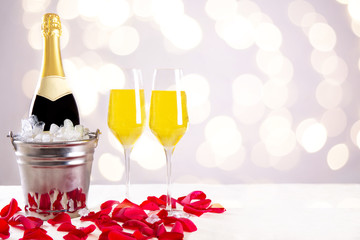 Champagner Flasche im Sektkühler mit Gläsern und Eis für eine Party vor einem bokeh Hintergrund