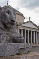Piazza Plebiscite, Naples, Italy - 06/14/2018: Lion statue in front of cathedral at Plebiscito square, Naples. Italian architecture concept. Travel concept. Ancient stone monuments in Italy.