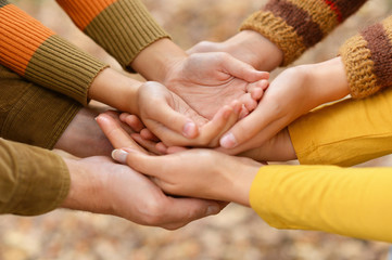 Hands of a family together on autumn background