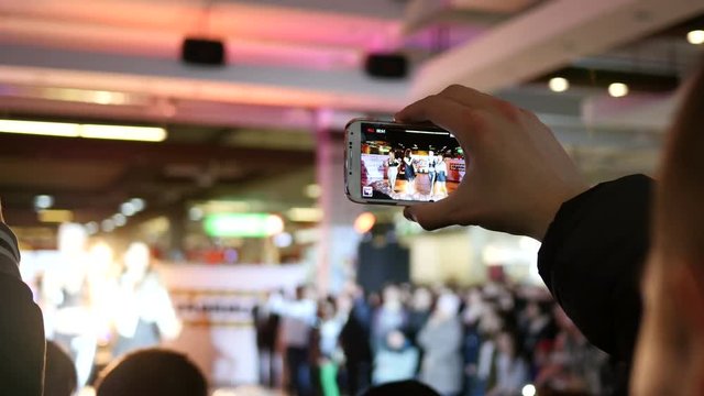 Spectators hands holding shooting video via smartphone of a concert performance
