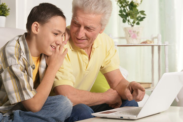 Grandfather with grandson using laptop at home