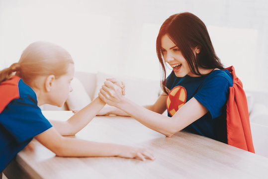 Mum And Daughter Arm Wrestling In Superhero Suits.