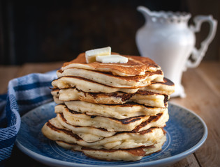 Close-up of stacked pancakes with butter on wooden background 