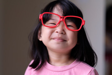 Naklejka premium Funny little asian child with a pair of big red glasses