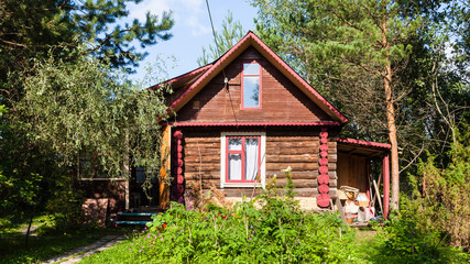 rural log house in green garden on summer day