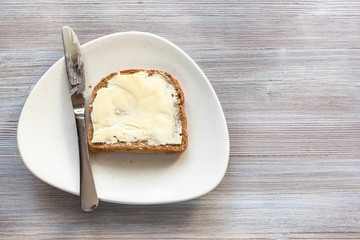 sandwich with butter and knife on white plate