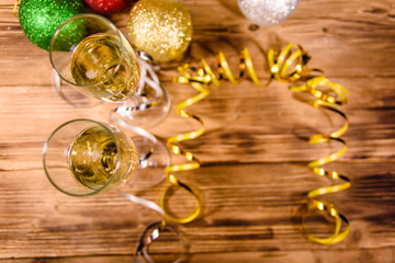 Two wineglasses with champagne and different christmas decorations on wooden table. Top view