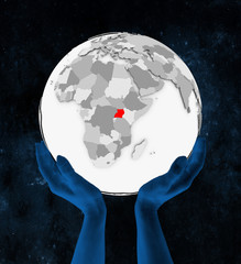 Uganda on white globe in hands