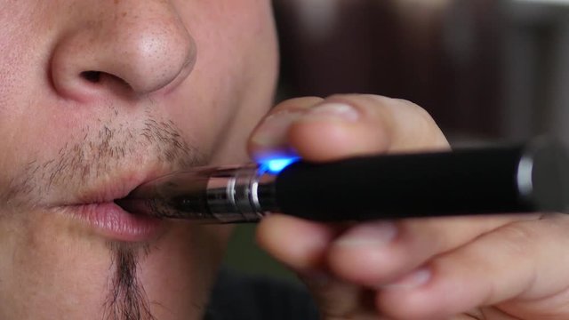 Closeup man mouth breathing out a smoke - smoking electronic cigarette