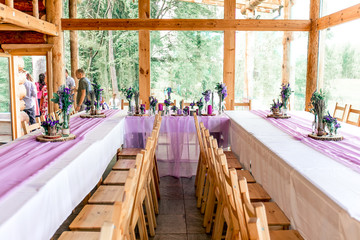 Purple lavender wedding. Table decor with dry lavender, green and white flowers. Candles, wooden rustic vases, Glass jars, lace bottles, sawed wood.
