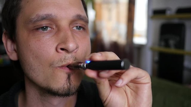 Breathing out a smoke rings in slow motion - man smoking electronic cigarette