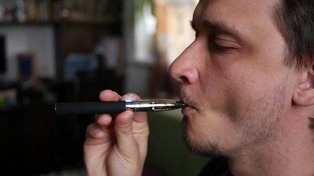 Man breathing out a smoke rings at home of electronic cigarette slow motion