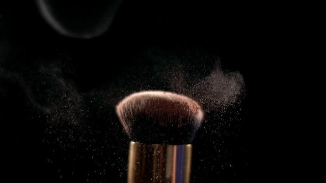 makeup brush with powder in slow motion on black background