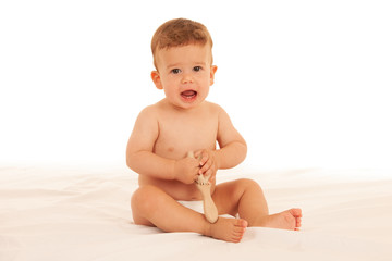 Hapy baby boy in playing on bed isolated over white