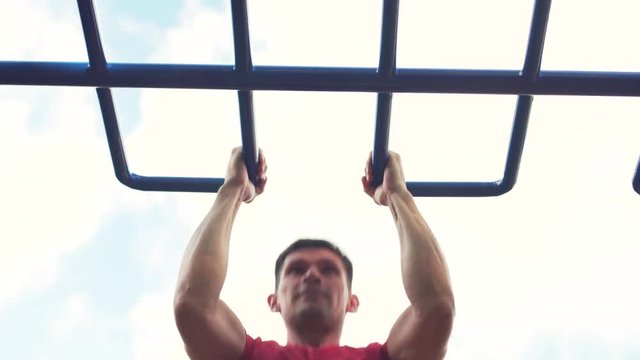 Young Fit Man Is Engaged in Street Workout. Male Athlete Doing Pull Ups on Parallel Bars. Summer Training in Park
