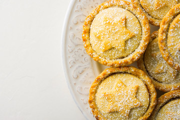 Traditional British Christmas Pastry Home Baked Mince Pies with Apple Raisins Nuts Filling on Vintage Plate White Kitchen Table. Golden Shortcrust Powdered. Top View Copy Space