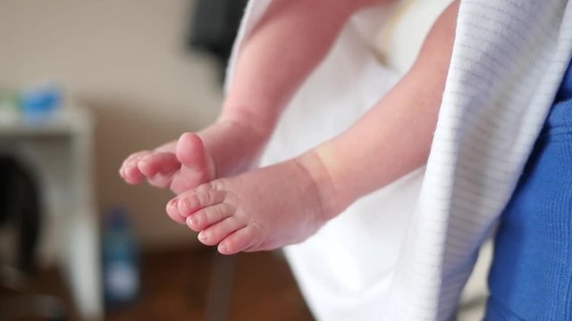 Little naked baby legs during infant lying on mother hands