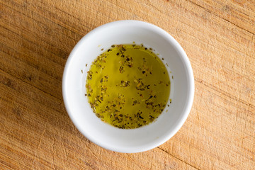 Small white bowl with seasoned virgin olive oil