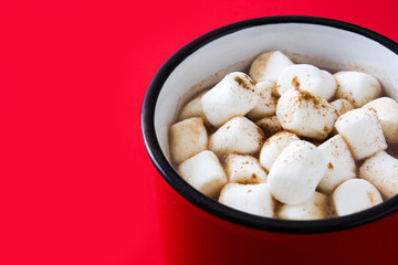 Christmas cocoa with marshmallow in mug on red background. 