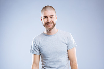Obraz premium Great mood. Delighted cheerful man smiling to you while standing against blue background