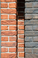 A part of wall made of red, dark brown and gray bricks