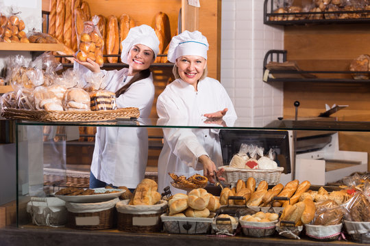 Bakery staff offering bread and different pastry for sale