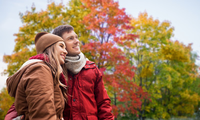 love, relationship and season concept - happy teenage couple hugging over autumn park background