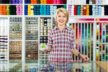 Mature glad woman customer picking various ribbon