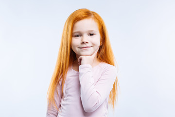 Fototapeta premium Smart child. Nice cheerful cute girl smiling while touching her chin