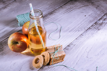 apple juice in bottle and biscuits on white wooden table